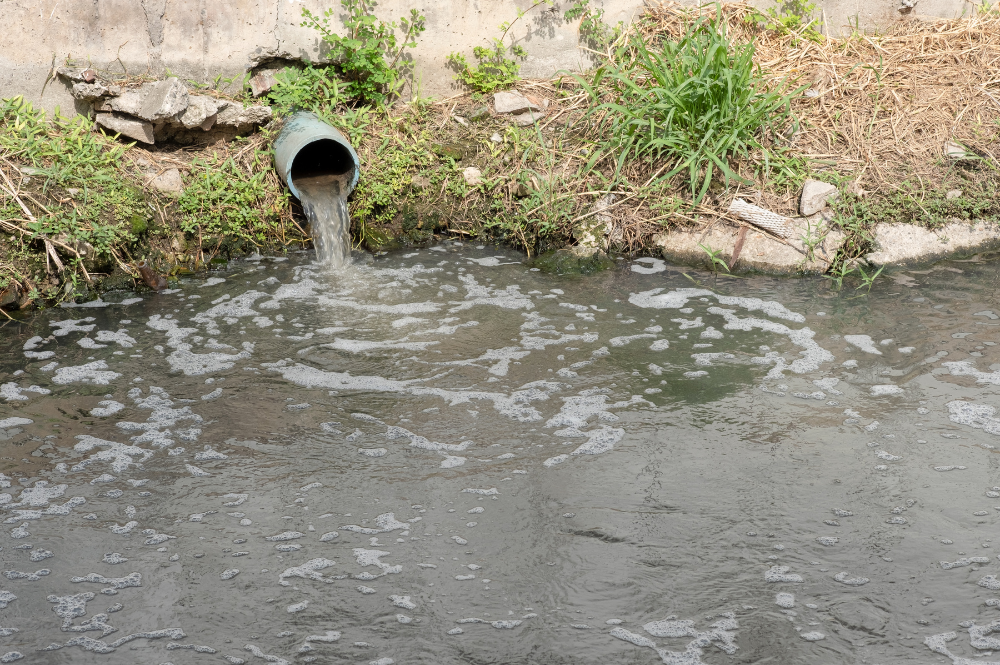 A pipe with water flowing out, representing stormwater compliance in the Boise area.
